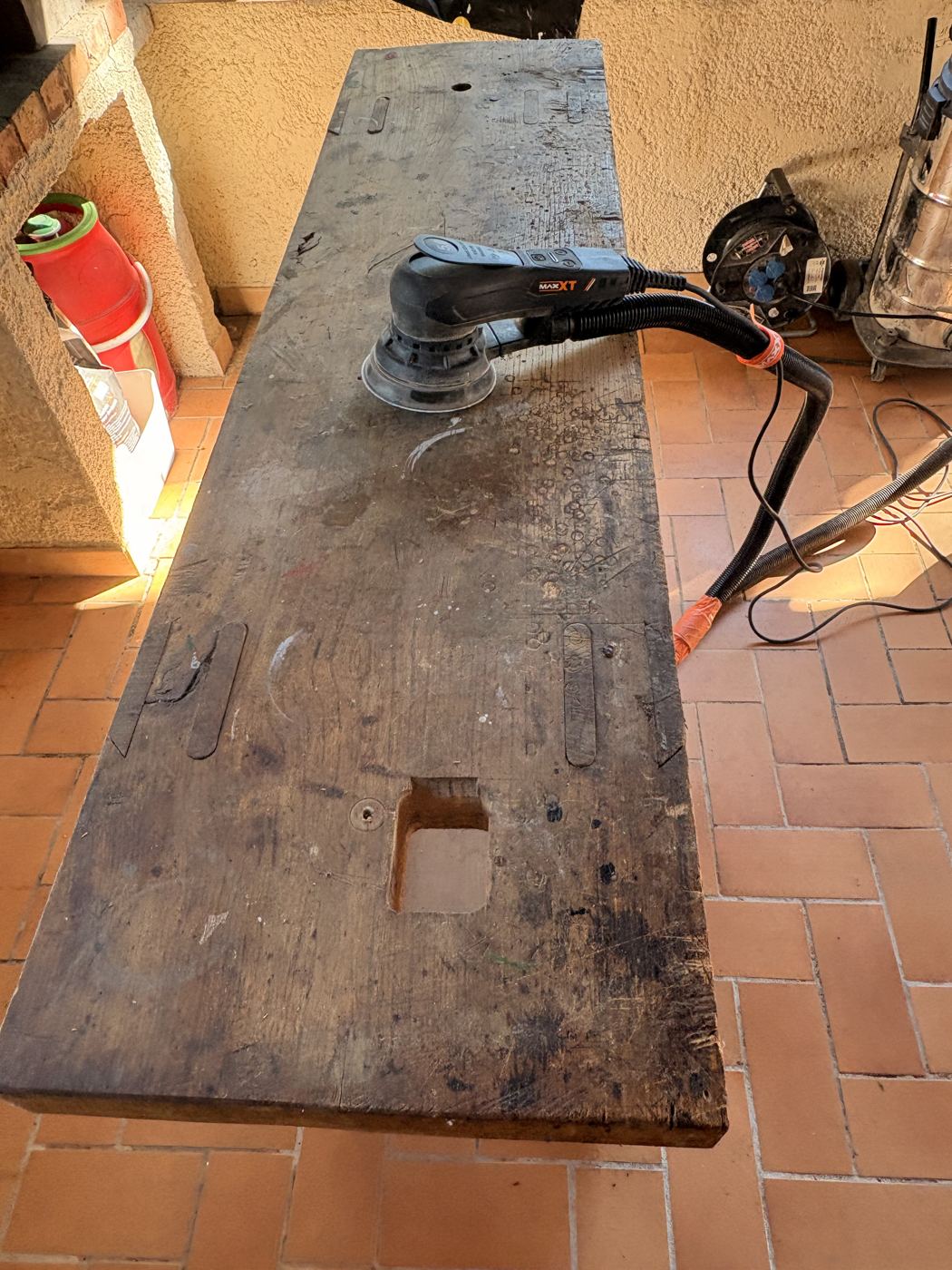 Ponçage en cours du plateau de l'établi ancien