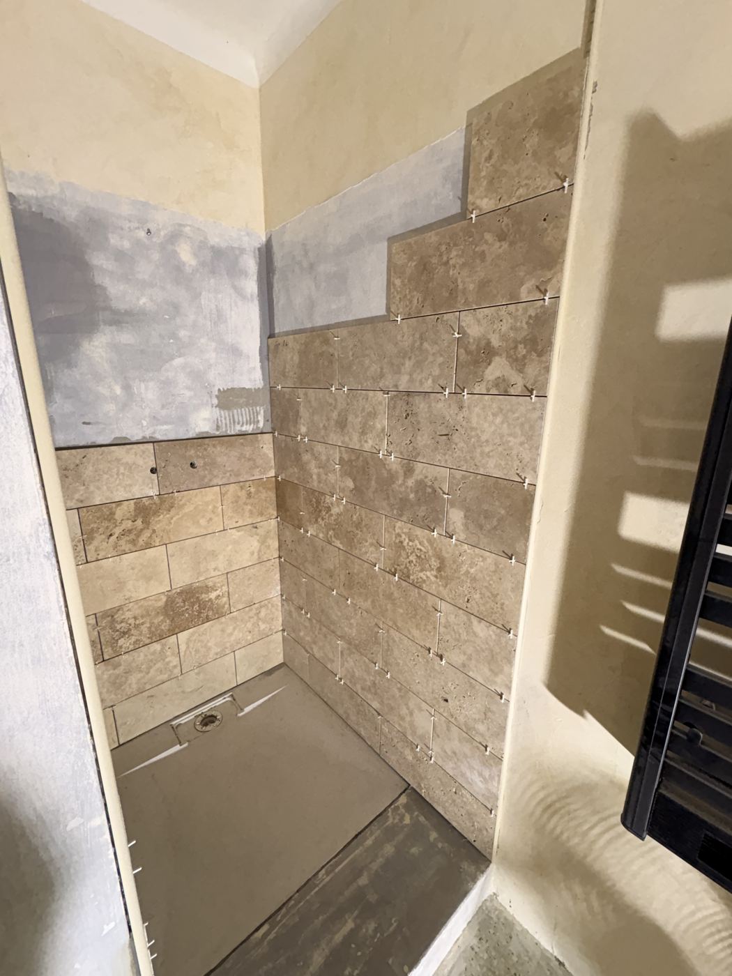 Pose du travertin en cours, mur en cours de carrelage